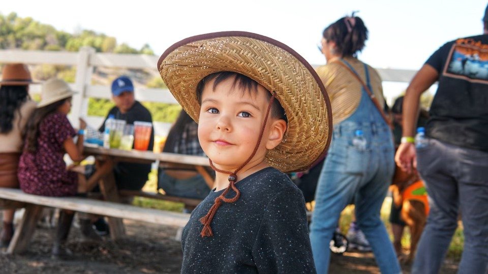 Young boy in a straw hat smiling at a family gathering